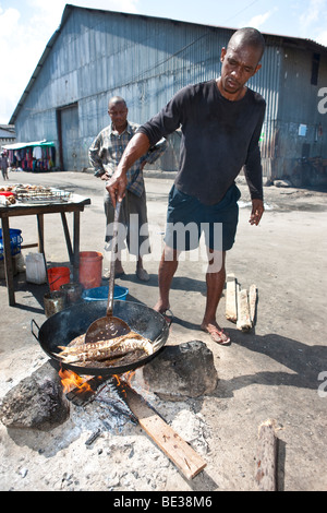 L'homme est un poisson à la cuisson au grilloir cookshop, Stonetown, Stone Town, Zanzibar, Tanzania, Africa Banque D'Images