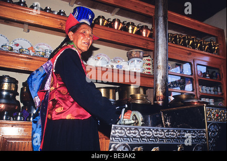Une vieille femme en costume traditionnel et un chapeau dans sa cuisine de Stok, Ladakh, Inde Banque D'Images