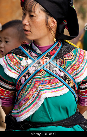 Femme de la tribu Yi dans Yuanyuang exerçant son enfant, Yunnan, Chine Banque D'Images