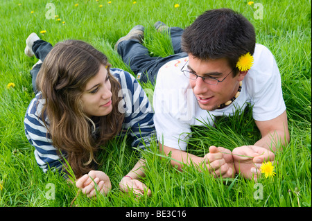 Jeune couple, étudiants, allongé sur une prairie de printemps et de parler les uns avec les autres, la France, l'Europe Banque D'Images