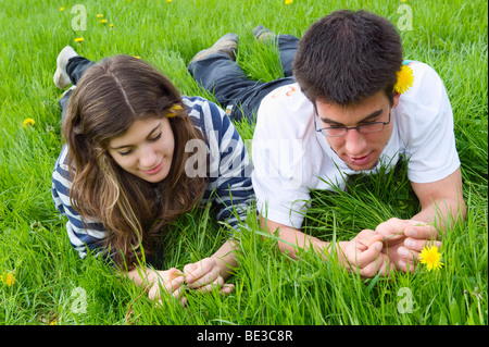 Jeune couple, étudiants, allongé sur une prairie de printemps et de parler les uns avec les autres, la France, l'Europe Banque D'Images