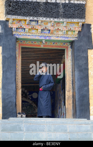 Thikse Monastery, manteau, vêtements traditionnels Ladakhis Goncha, l'utilisation d'un téléphone mobile, le couvent est peint avec porte et relief Banque D'Images