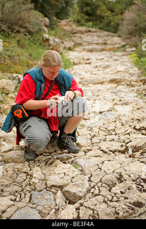 Jeune femme de prendre une photo d'une plante sur le chemin, le plateau de Lassithi, Crète, Grèce Banque D'Images