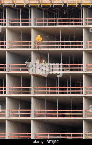 Grand site en construction, matériaux containers suspendu par une grue en face d'une enveloppe du bâtiment est en cours de déchargement, Dusseldorf Medi Banque D'Images