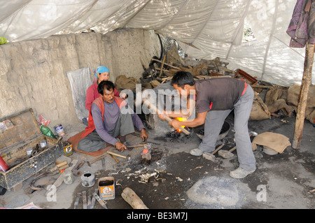 Forgeron avec son épouse et la fabrication pour l'assistant de faucilles la récolte de céréales dans une tente, Shey, Ladakh, Inde, Himalaya, un Banque D'Images