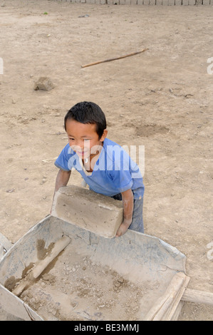 Petit garçon le chargement d'une brouette avec des briques dans une briqueterie qui fabrique des briques séchées à l'air dans la vallée de l'Indus, Traktok, La Banque D'Images