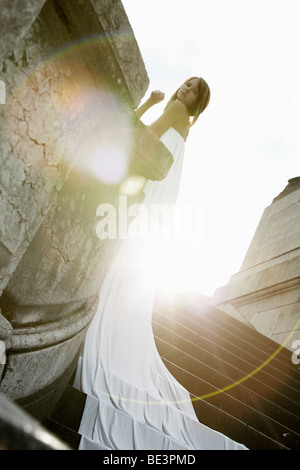 Photo de Mode d'une jeune femme blonde en robe blanche avec long train s'appuyant sur le garde-fou du pont Alexander, Pa Banque D'Images
