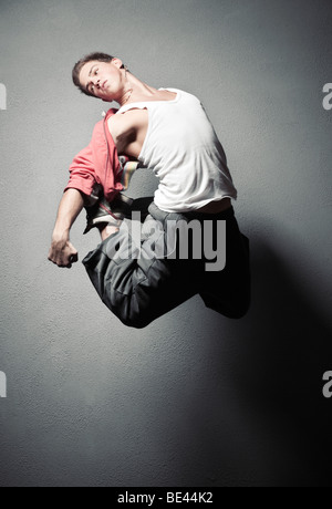 Jeune homme de saut. Sur fond de murs en pierre. Banque D'Images