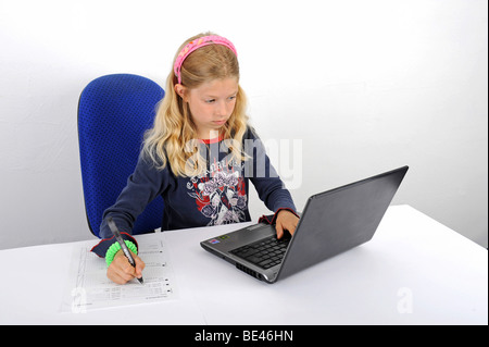 Jeune écolière fait ses devoirs avec un ordinateur portable Banque D'Images