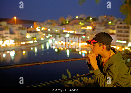Jeune garçon en profitant de la vue d''Agios Nikolaos, dans la soirée, l'île de Crète, Grèce Banque D'Images