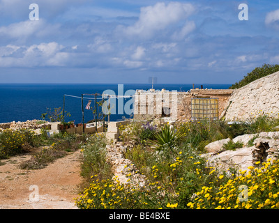 Une maison de campagne en pierre, le long de certaines berges rocheuses par la Méditerranée près de Wied iz Zurrieq, Malte. Banque D'Images