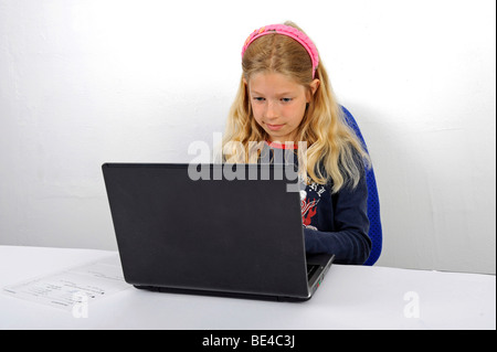 Jeune écolière fait ses devoirs avec un ordinateur portable Banque D'Images