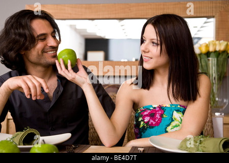 Jeune couple à la table à manger, femme donnant à l'homme tout un apple Banque D'Images