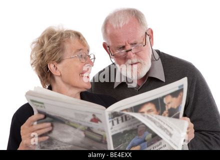 Couple de retraités plus âgés journal lecture ensemble, épouse souriant à son mari. Banque D'Images