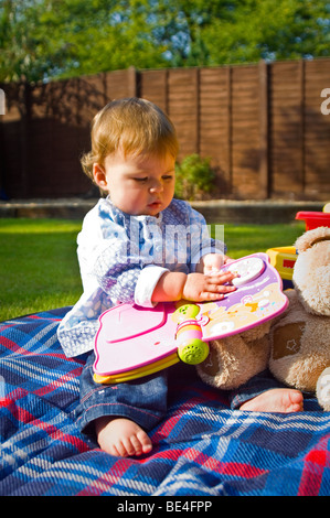 Portrait vertical d'une jeune fille s'amusant à jouer avec ses jouets à l'extérieur, au soleil. Banque D'Images