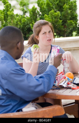 Couple Interacial, (African American male teen and Caucasian teenage girl)assis dehors et manger le déjeuner et des collations saines Banque D'Images