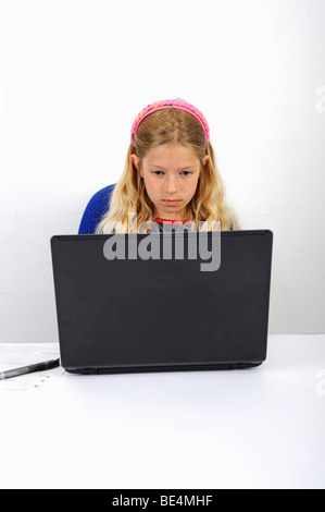 Jeune écolière fait ses devoirs avec un ordinateur portable Banque D'Images