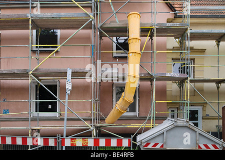 Maison échafaudée avec chute de débris, poubelles et marquages de sécurité Banque D'Images