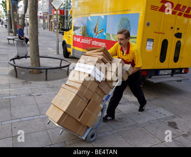 Transporteur de colis Michael Meindel l'équilibre entre une pile de paquets dans la rue avec son chariot pour l'allemand Deutsche Post mail Banque D'Images