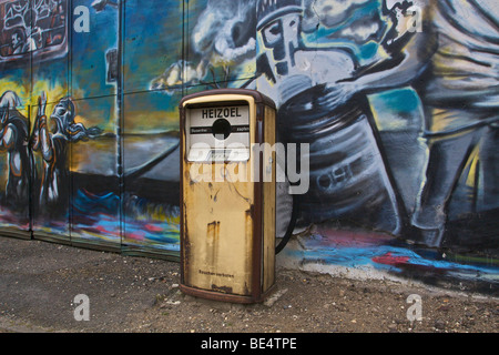 Ancienne pompe à essence pour l'huile de chauffage à l'abandon de l'usine en face de mur pulvérisé avec graffiti Banque D'Images