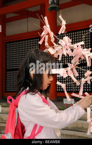 Japanese girl noeuds prières et voeux aux arbustes dans le Sanctuaire Heian Shinto, Kyoto, Japon, Asie Banque D'Images