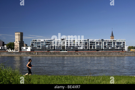 Jogger sur les bollards meadows en face de l'Wohnwer(f)t des immeubles d'habitation et la tour historique à la Rhei Bayenturm Banque D'Images