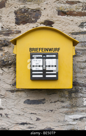 Ancienne boîte aux lettres métal jaune sur un mur de fondation en pierre Banque D'Images