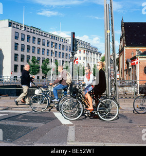 Femme élégante cycliste de banlieue en attente avec groupe de personnes sur des vélos sur une rue, à un carrefour en été à Copenhague Denmar KATHY DEWITT Banque D'Images