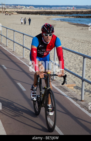 Homme randonnée à vélo sur la promenade en voie cyclable avec des hommes d'exécution de la formation sur la plage Palma Majorque Banque D'Images