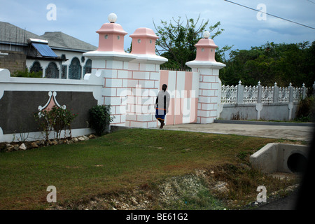 Homme marchant près de la porte avant d'un complexe à la Jamaïque. Banque D'Images