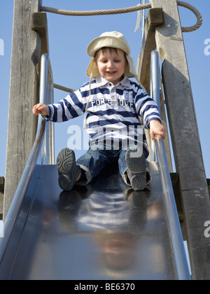 Jeune garçon, 2 ans, assis sur une diapositive Banque D'Images
