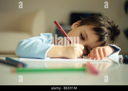 Little Boy resting head on arm, le dessin avec des crayons de couleur Banque D'Images