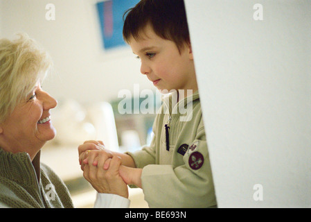 Petit garçon face à face avec grand-mère, holding hands Banque D'Images