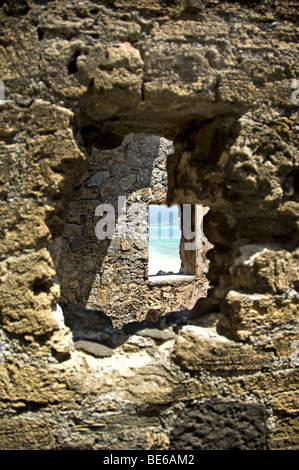 Voir à travers le trou dans le mur et un autre trou de la fenêtre de phare montrant le sable blanc et bleu de la mer au soleil l'Ile Maurice Banque D'Images