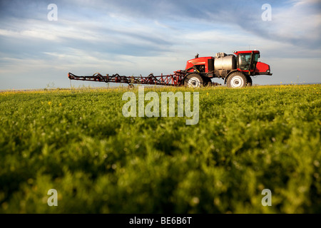 Un pulvérisateur enjambeur sur un champ dans un paysage de prairie Banque D'Images