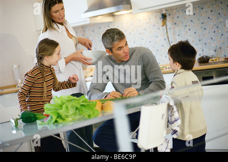 Famille ensemble dans la cuisine à l'écoute de tous les petit garçon Banque D'Images