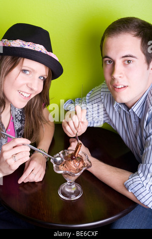 Deux des jeunes partageant une glace au chocolat avec un café en flocons dans un endroit frais. Banque D'Images