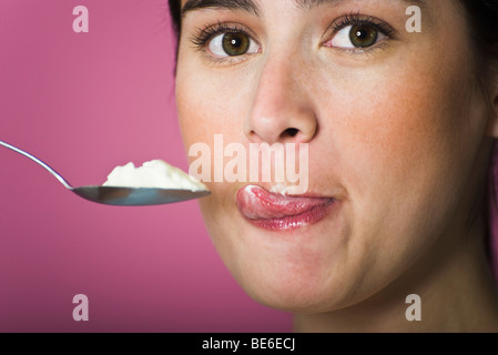 Femme avec cuillère pleine de crème glacée, en se léchant les lèvres Banque D'Images