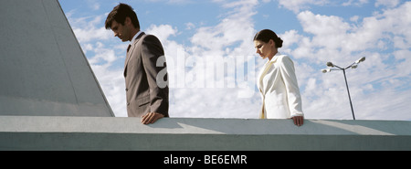 Businessman and businesswoman on rooftop, tant à la recherche vers le bas était Banque D'Images