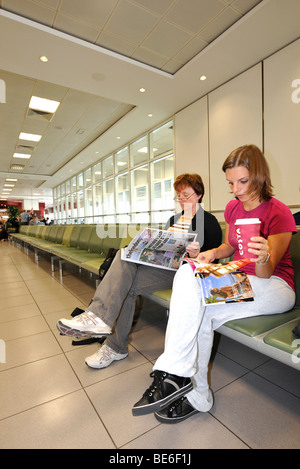 Les passagers assis dans la salle d'attente en face de la porte d'embarquement, BAA Heathrow International Airport, Terminal 4, Londres, Angleterre Banque D'Images