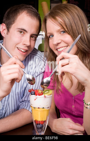 Trendy young couple un kniccurbockerglory (un fruit tropical sundae) dans un endroit frais et café. Banque D'Images