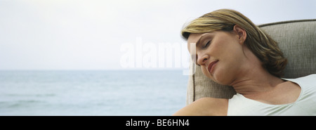 Femme dormir dans un fauteuil, mer ouverte en arrière-plan Banque D'Images