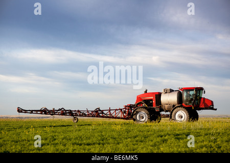 Un pulvérisateur enjambeur sur un champ dans un paysage de prairie Banque D'Images