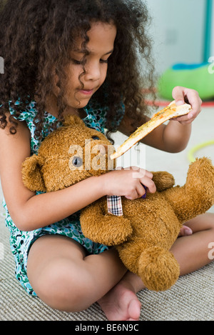 Petite fille ours alimentation pizza Banque D'Images