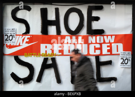 Un homme passe une vitrine mondiale des sports une publicité vente de chaussures dans le centre de Londres Banque D'Images