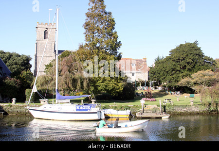 Le Prieuré de Wareham Quay - Dame de l'église St Mary à l'arrière-plan et un couple dans un petit bateau à moteur passant Banque D'Images