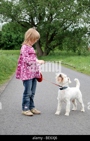 Fille, 5, jouant fetch-le-stick avec un schnauzer nain Banque D'Images