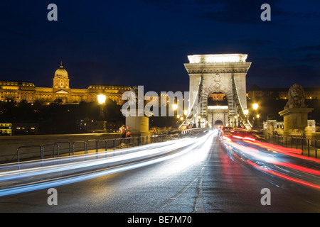 Soirée animée le trafic traversant le Pont des chaînes de Budapest avec le Palais Royal à l'arrière-plan Banque D'Images