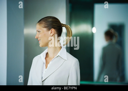 Businesswoman sortant d'ascenseur, smiling Banque D'Images