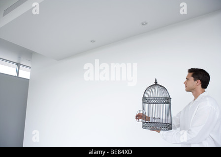 Man holding empty cage à oiseaux avec porte ouverte, side view Banque D'Images